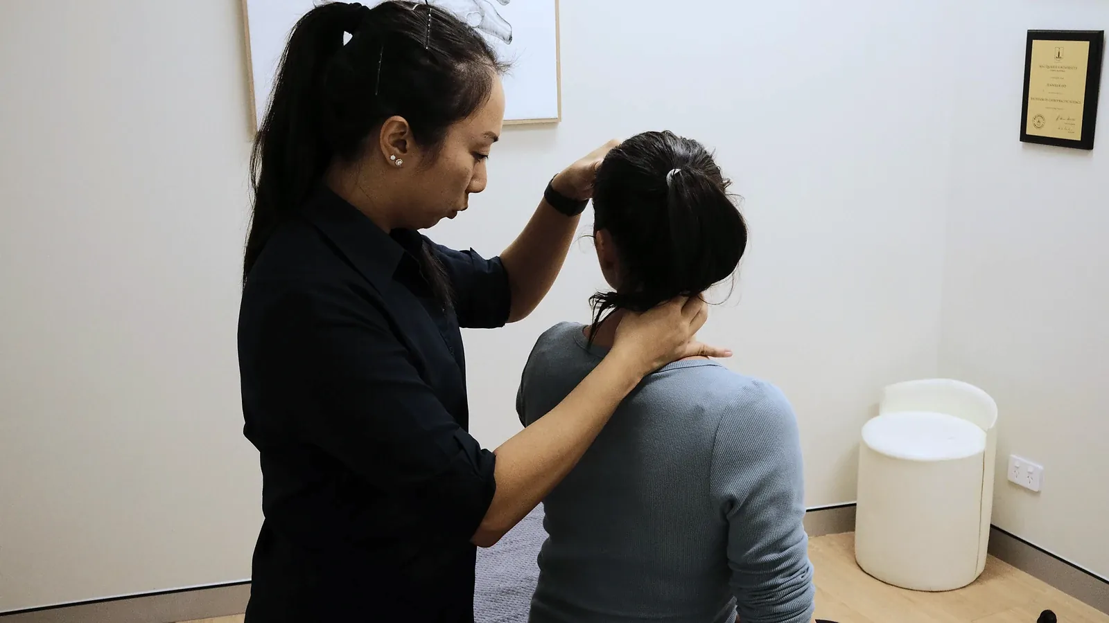 Chiropractor assessing a seated patient’s neck and shoulder alignment in the Ashfield clinic